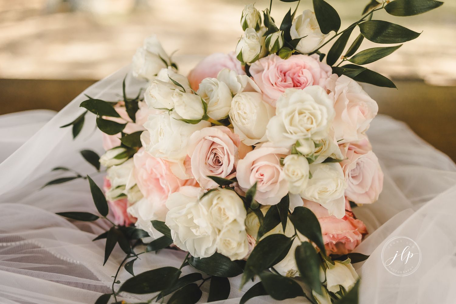 Romantic floral arrangement of blush pink and cream roses with green foliage.