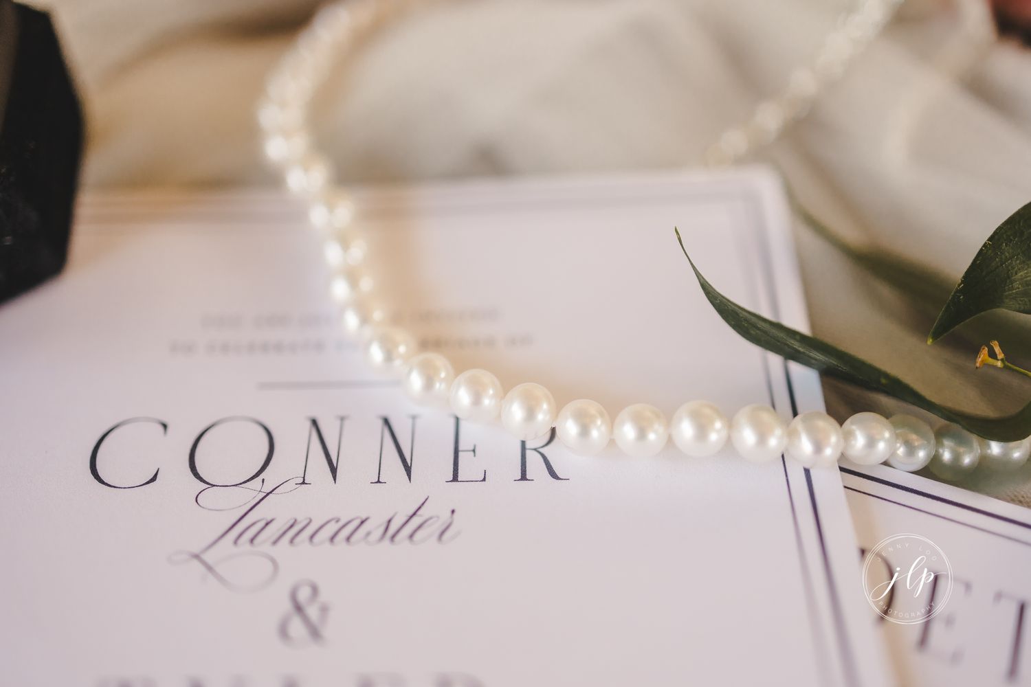 Close-up of wedding invitation suite with classic typography on white tulle background.