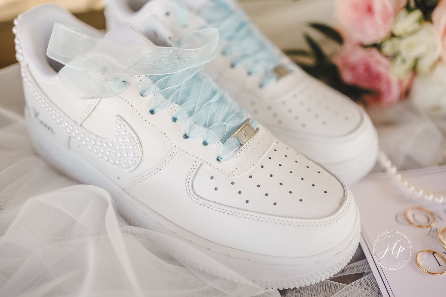White Nike sneakers displayed with wedding details and pearl accessories.