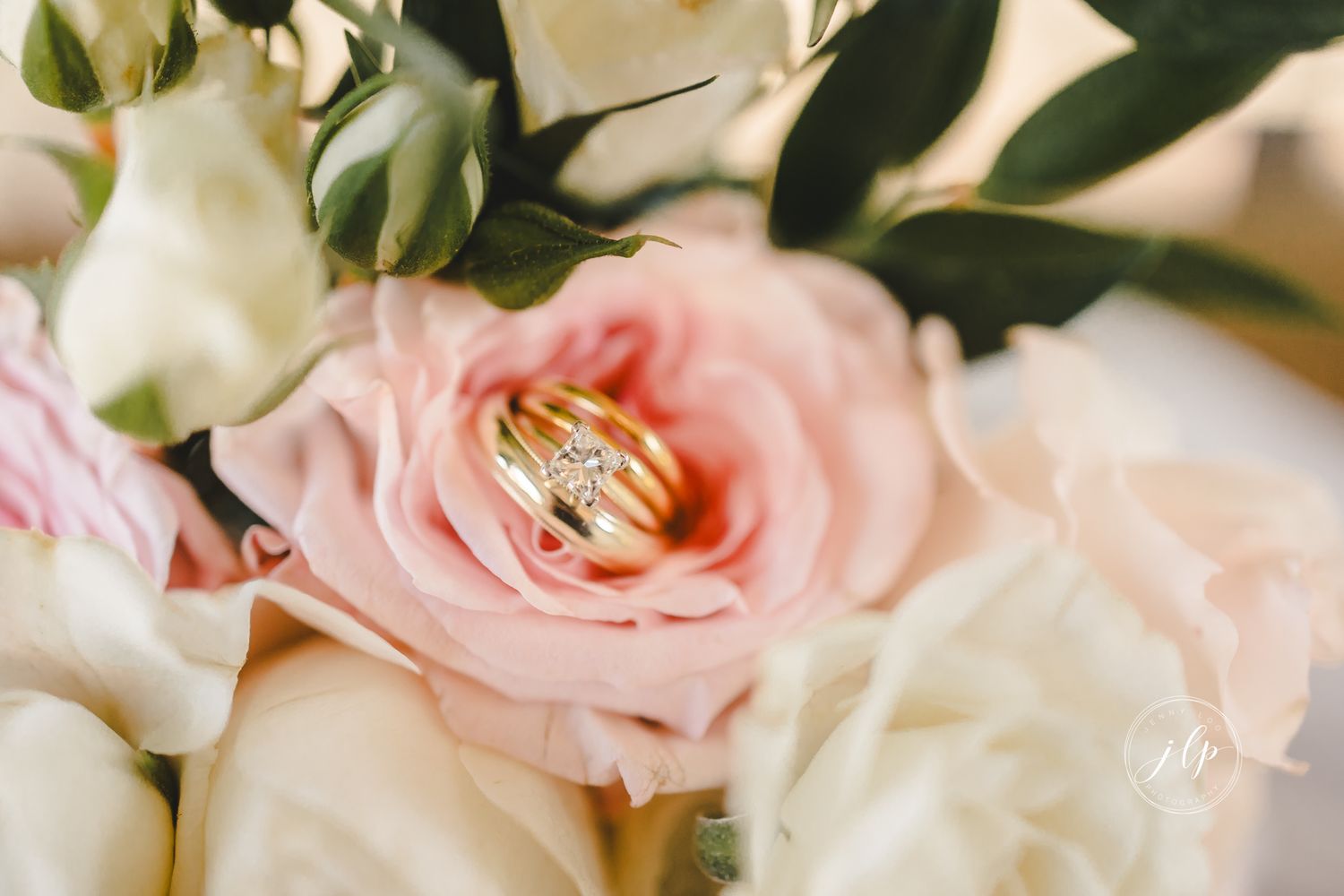 Soft pink and white roses arranged with greenery for wedding decor.