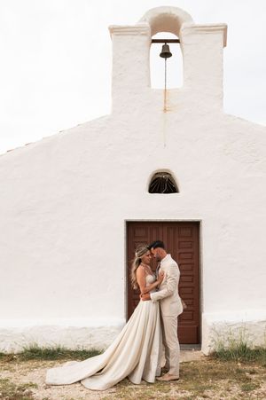 Romantic wedding photos against a white church exterior with wooden doors.