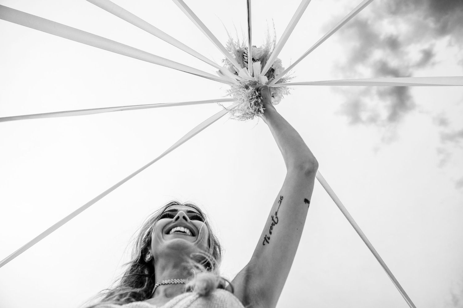 Looking up at white umbrella spokes against cloudy sky in artistic composition.
