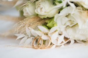 Delicate white wedding flowers and rings arranged in soft focus.