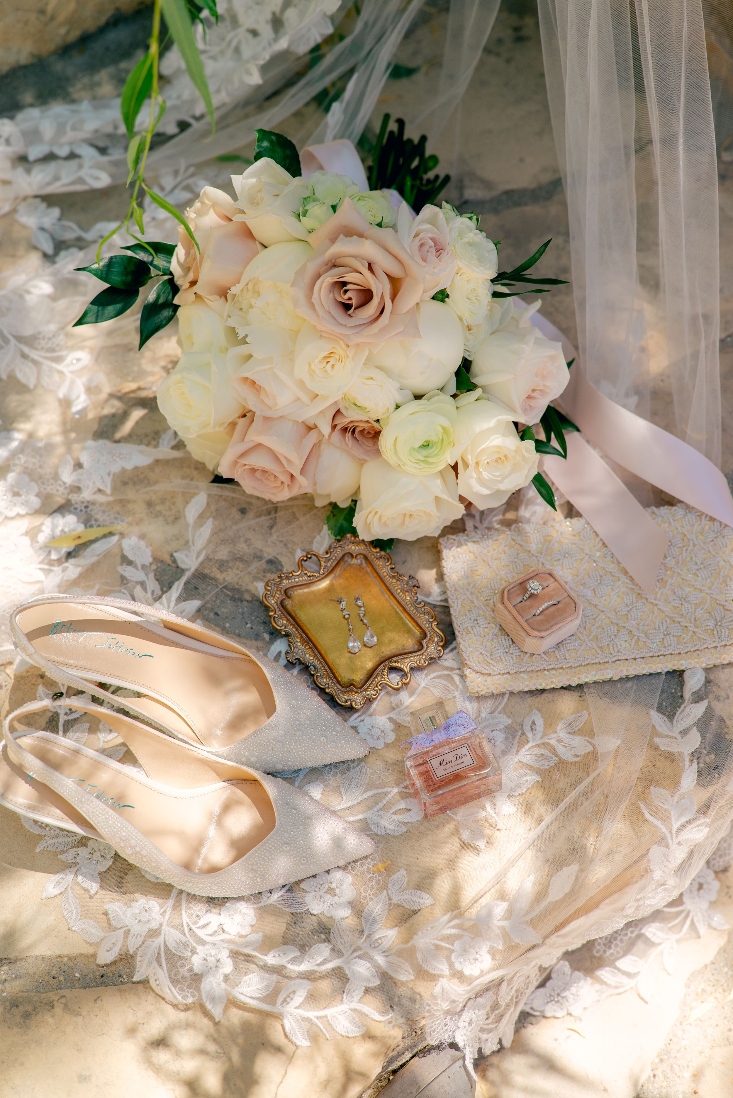 Wedding accessories including bouquet, shoes, and delicate lace details in soft blush tones.
