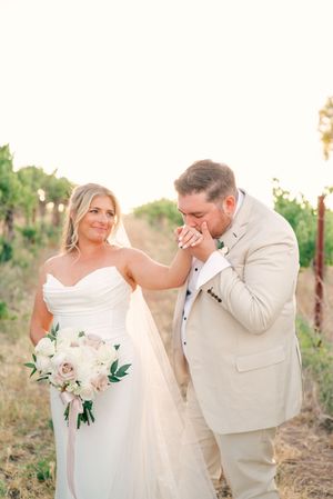 Romantic wedding couple sharing intimate moments in a sunlit vineyard setting.