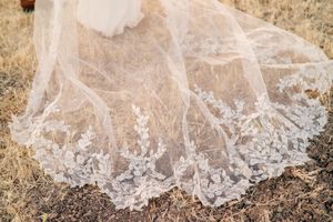 Close-up detail of intricate lace wedding veil spread across natural terrain.