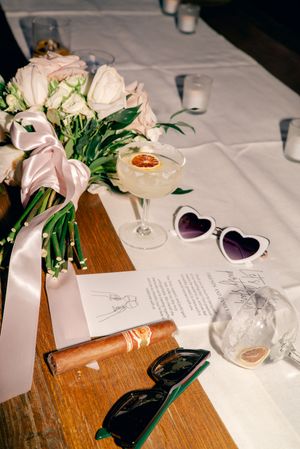 Wedding reception table detail with pink roses, heart-shaped glasses and paper details.