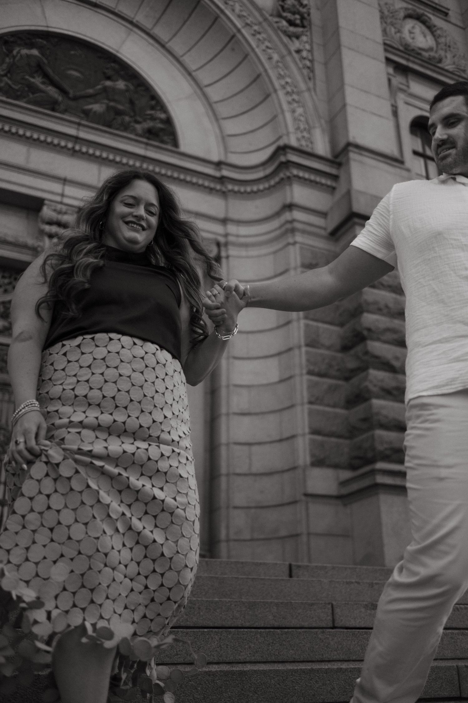 a man holding a woman's hand as they walk down the stairs while being captured by English speaking photographer for tourists in Stockholm