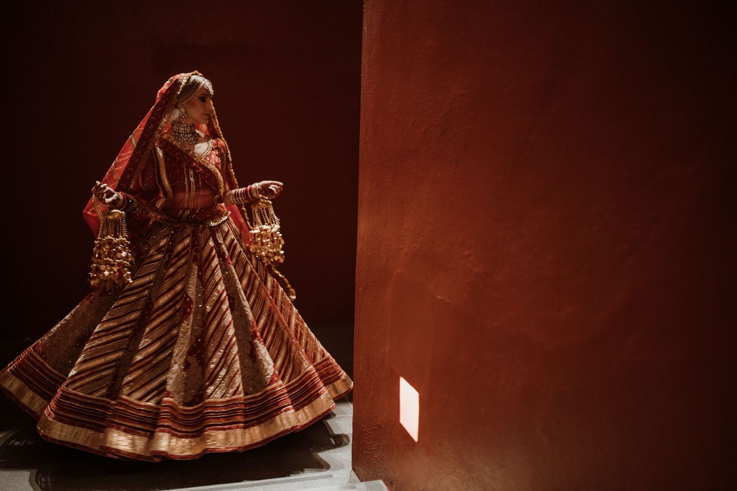 Rich burgundy lehenga with intricate embroidery and traditional Indian wedding details.