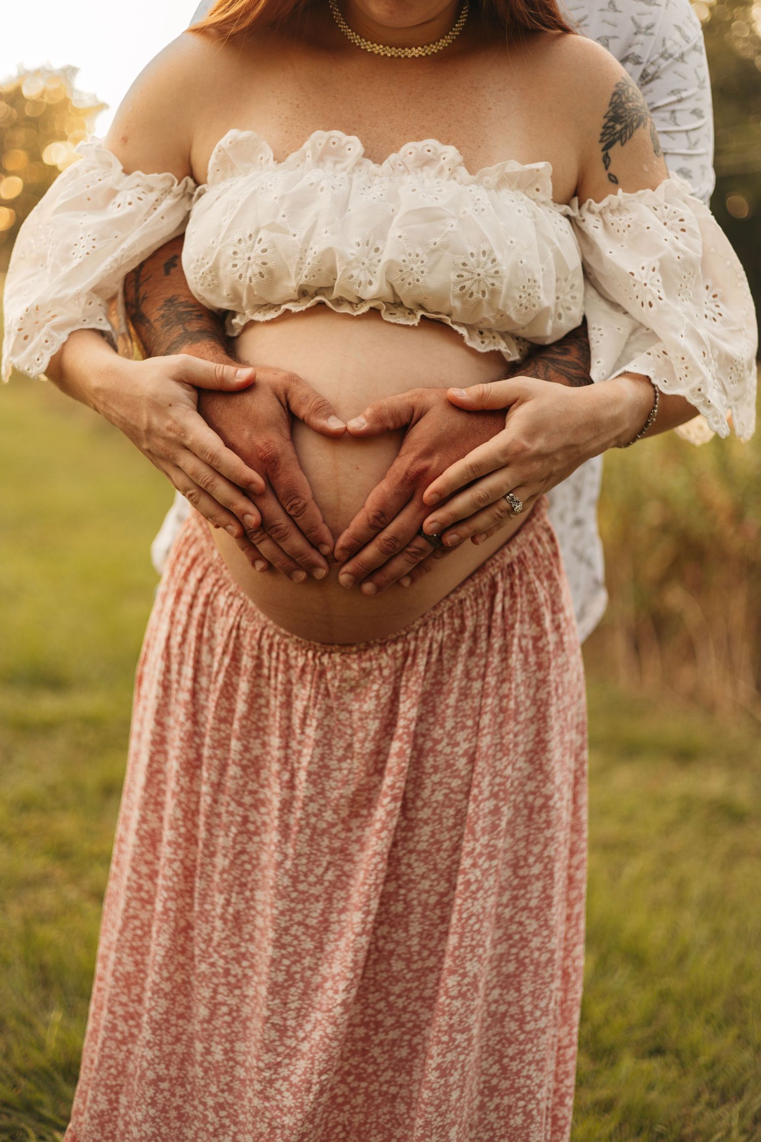 Maternity photography session in Central Mississippi featuring a pregnant mother outdoors in a field with hands on her baby bump.