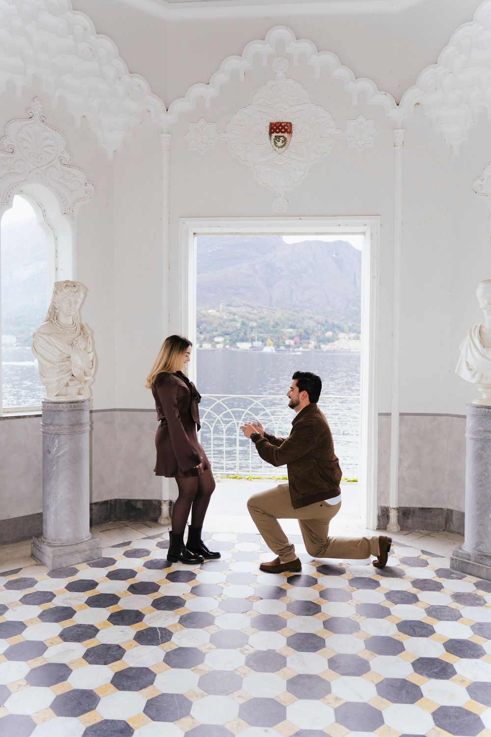 A romantic proposal sequence showing a couple in a white room with geometric floor tiles and mountain views through windows.