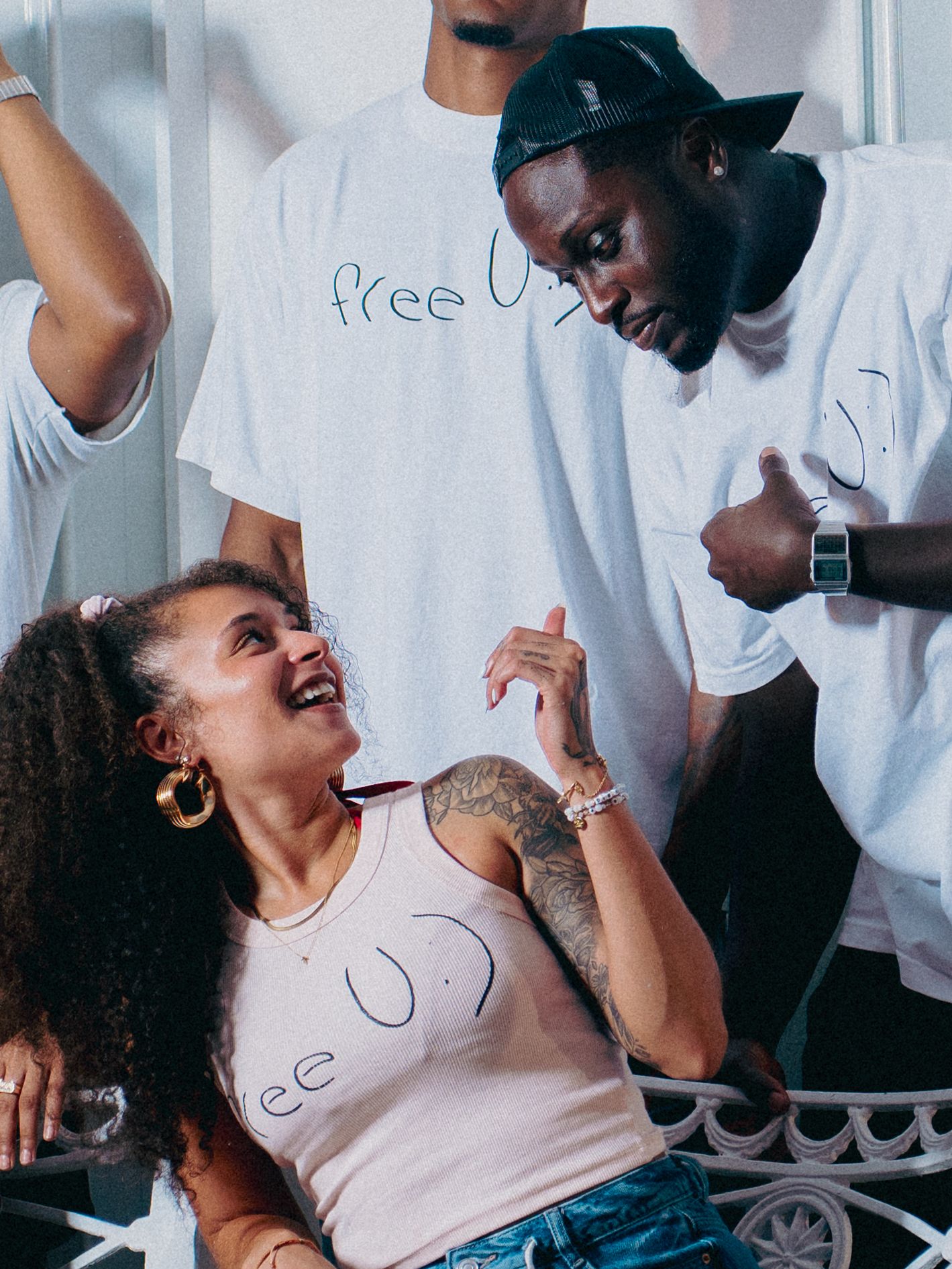 A group of people in white t-shirts laugh and smile together during what appears to be a joyful gathering.