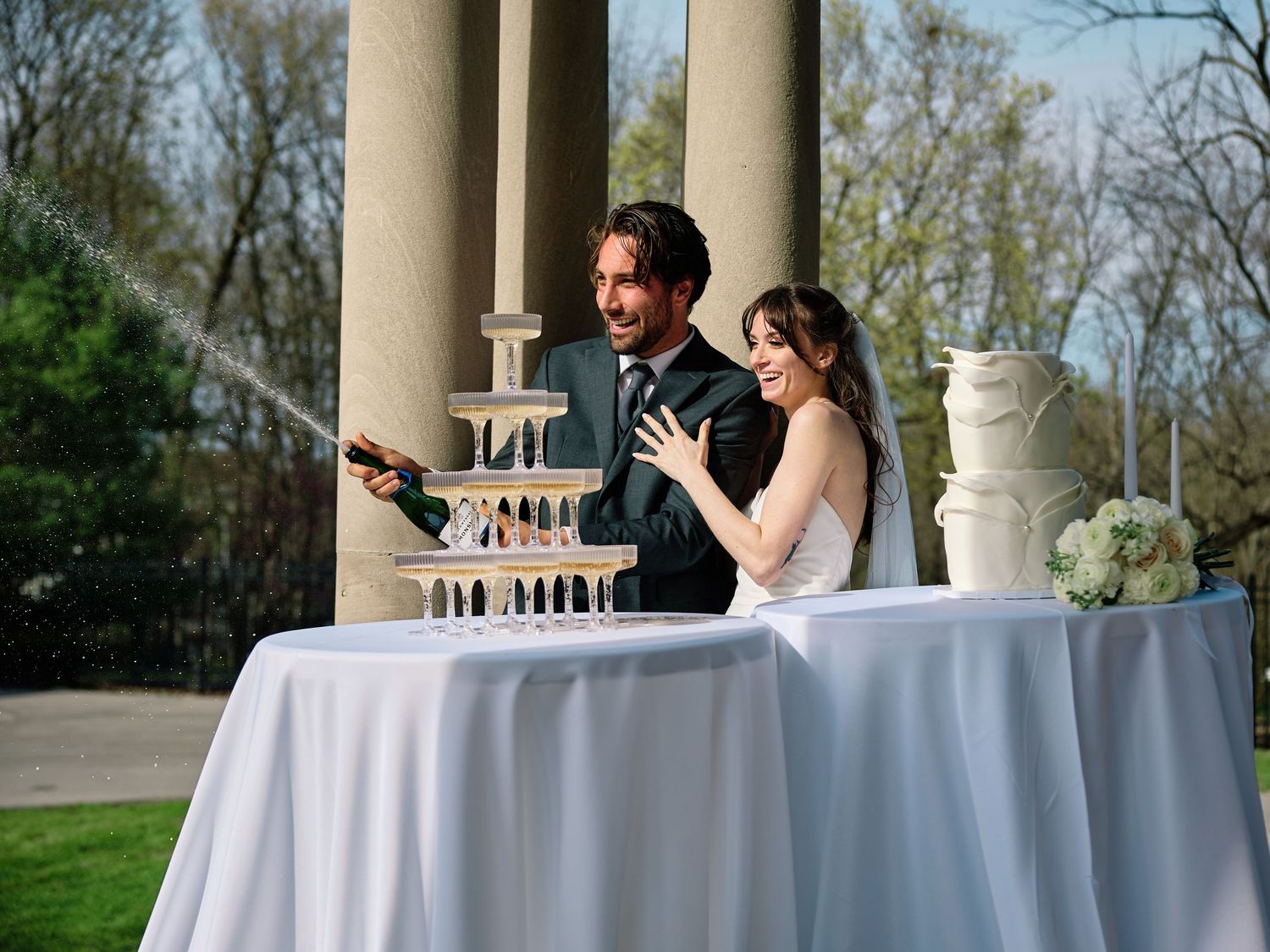 Wedding reception scene with white cake and turquoise background as couple shares intimate moment.