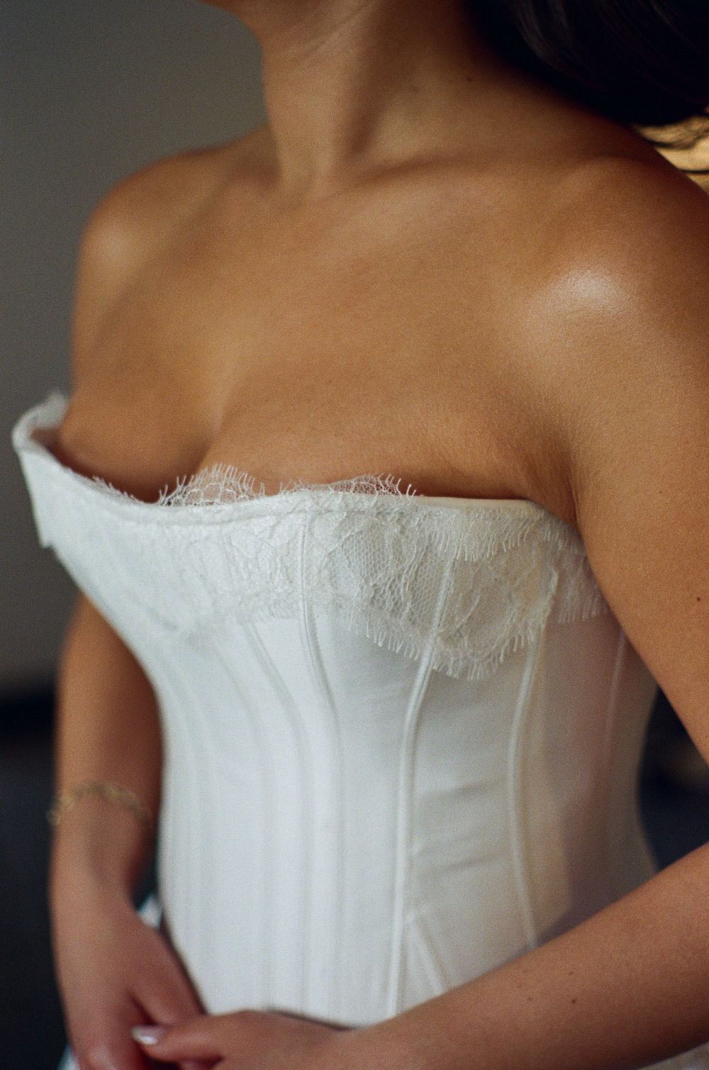Woman wearing a white strapless lace corset bridal bodice with boning details and delicate lace trim.