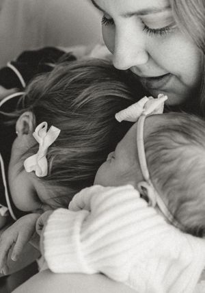 Close up tender moment with hair bows and soft lighting in black and white.