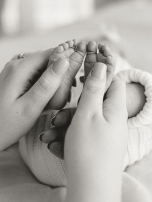 Close up black and white photo of hands gently holding tiny baby feet.