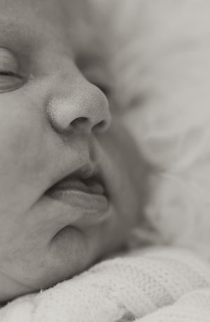 Black and white macro shot showing peaceful sleeping infant's nose and lips.