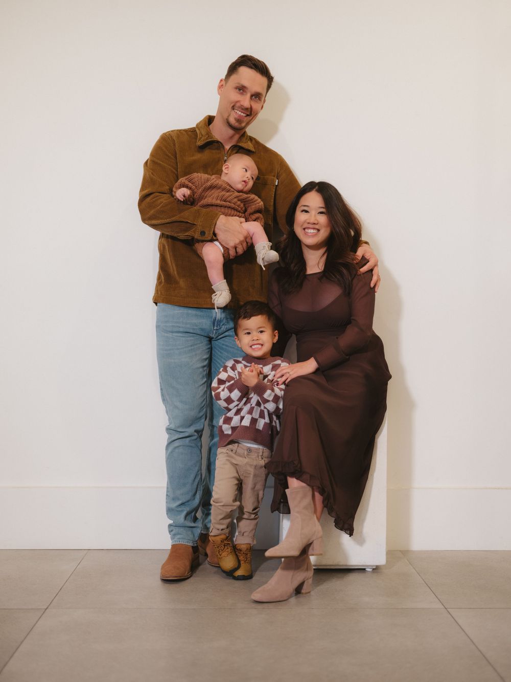 A family portrait in warm tones against a white studio background.
