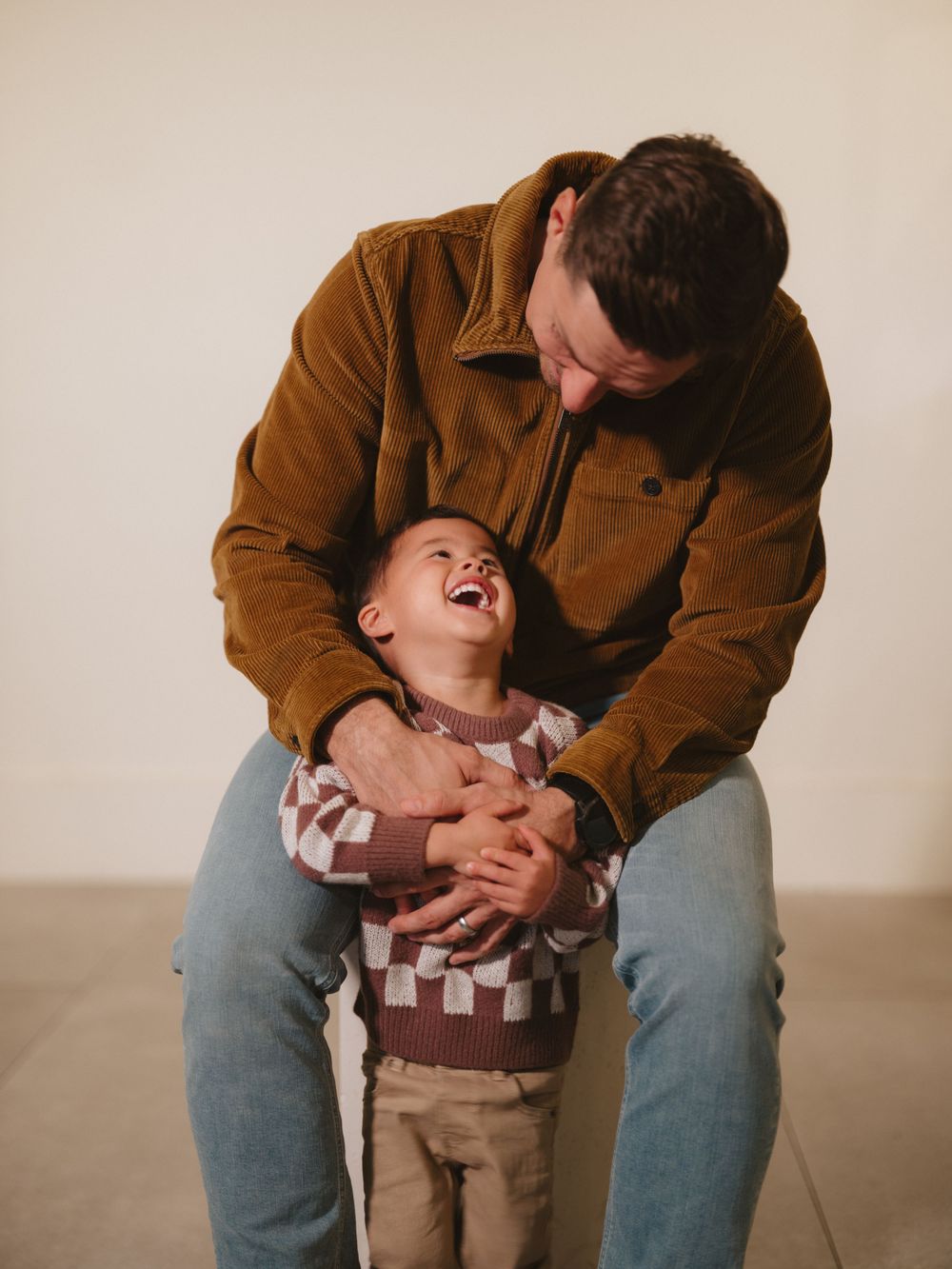 A touching candid moment captured between parent and child in a studio setting.