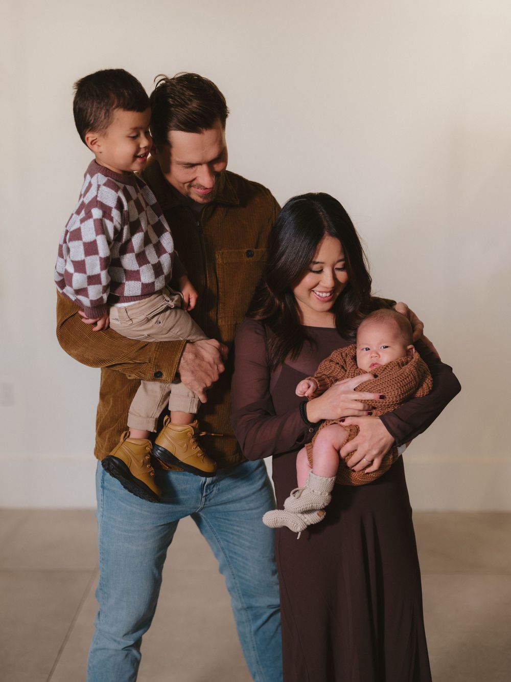 A heartwarming family portrait with parents holding their children in a studio setting.