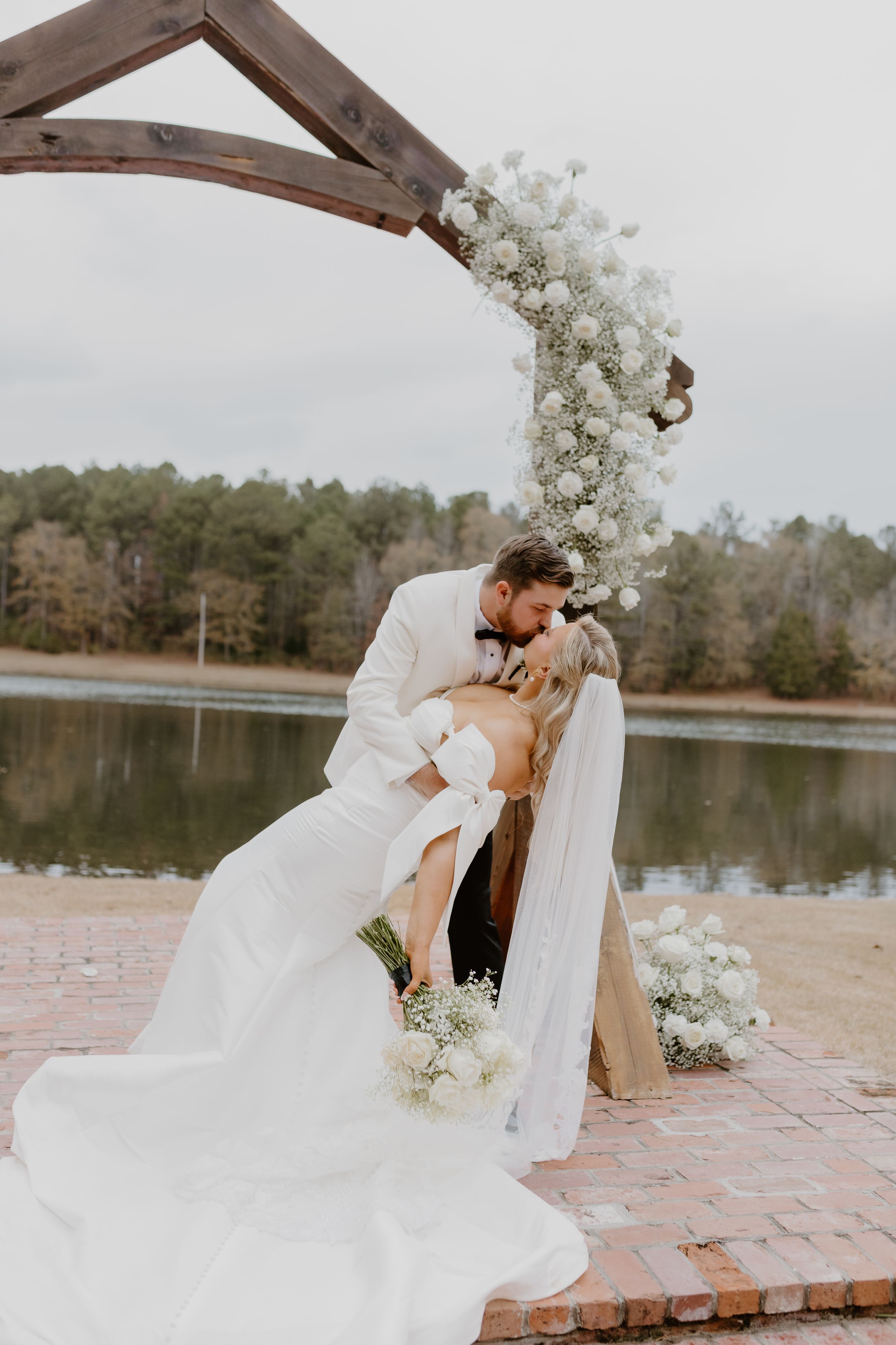 Close-up portrait surrounded by lush peach and pink floral arrangements in romantic outdoor setting.