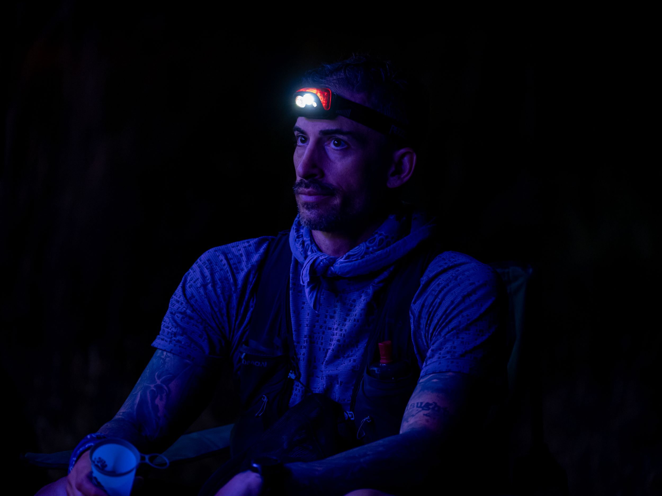 Runner wearing a headlamp illuminated in blue light during a nighttime activity.