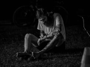 Black and white image of a runner adjusting equipment during a nighttime race.
