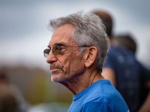 Profile shot of a spectator wearing glasses watching an outdoor sporting event.
