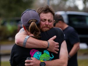 Two people share a supportive hug at what appears to be a sporting event.