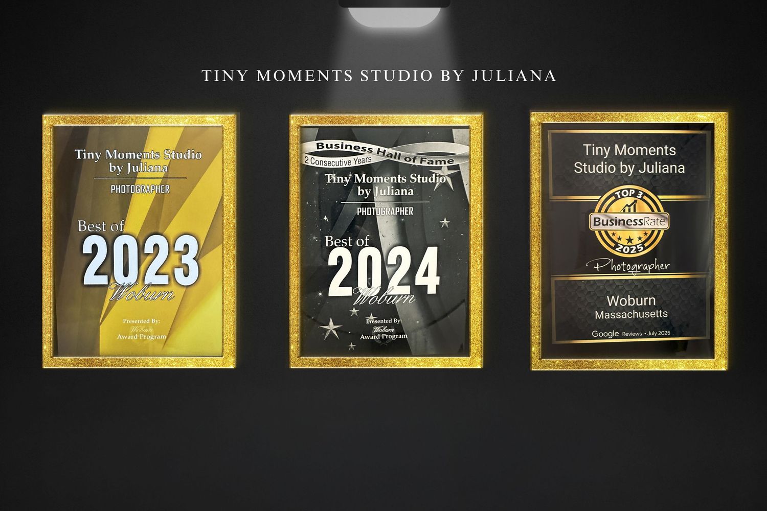 Two golden circular award badges for Tiny Moments Studio displaying Best of 2023 and Best of 2024 on black display stand.
