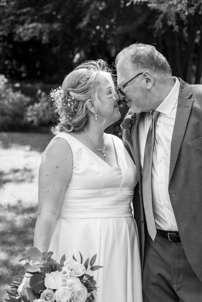 Black and white close-up of loving couple sharing tender moment with floral bouquet.