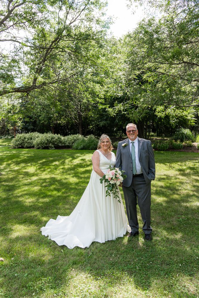 A wedding portrait in a garden setting with lush greenery in the background.