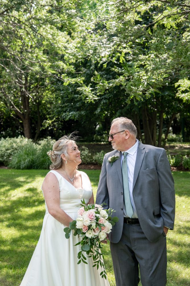 A happy couple shares a joyful moment outdoors in a park setting during their wedding ceremony.