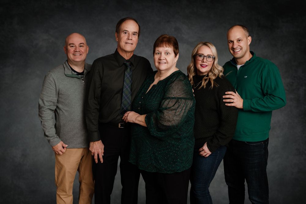 Professional studio portrait of family members posing together against a dark backdrop.