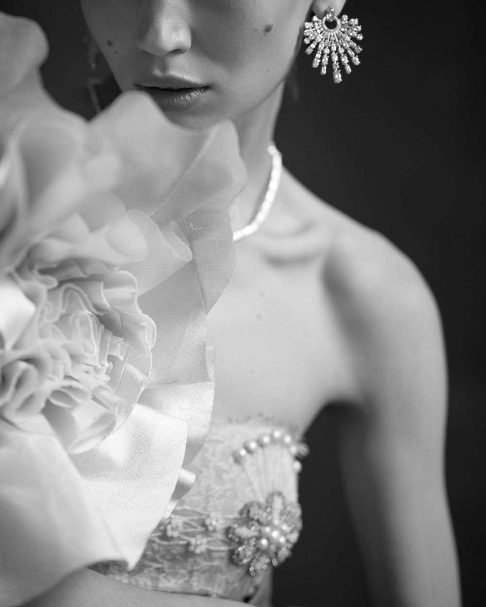 Elegant black and white bridal portrait showcasing delicate lace, ruffles, and sparkling starburst earring details.