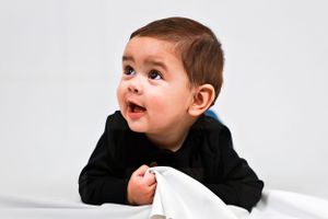 Young child in black sweater laying on white Carlsbad Roswell Artesia Hobbs New Mexico NM Photography Maternity Milestones Newborn Pictures