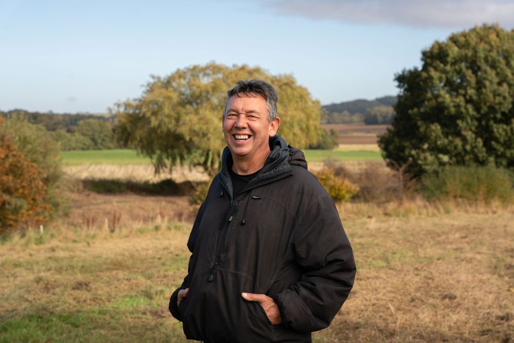 Person enjoying a casual moment outdoors in a black hoodie against an autumn rural landscape. Lincolnshire branding photographer.