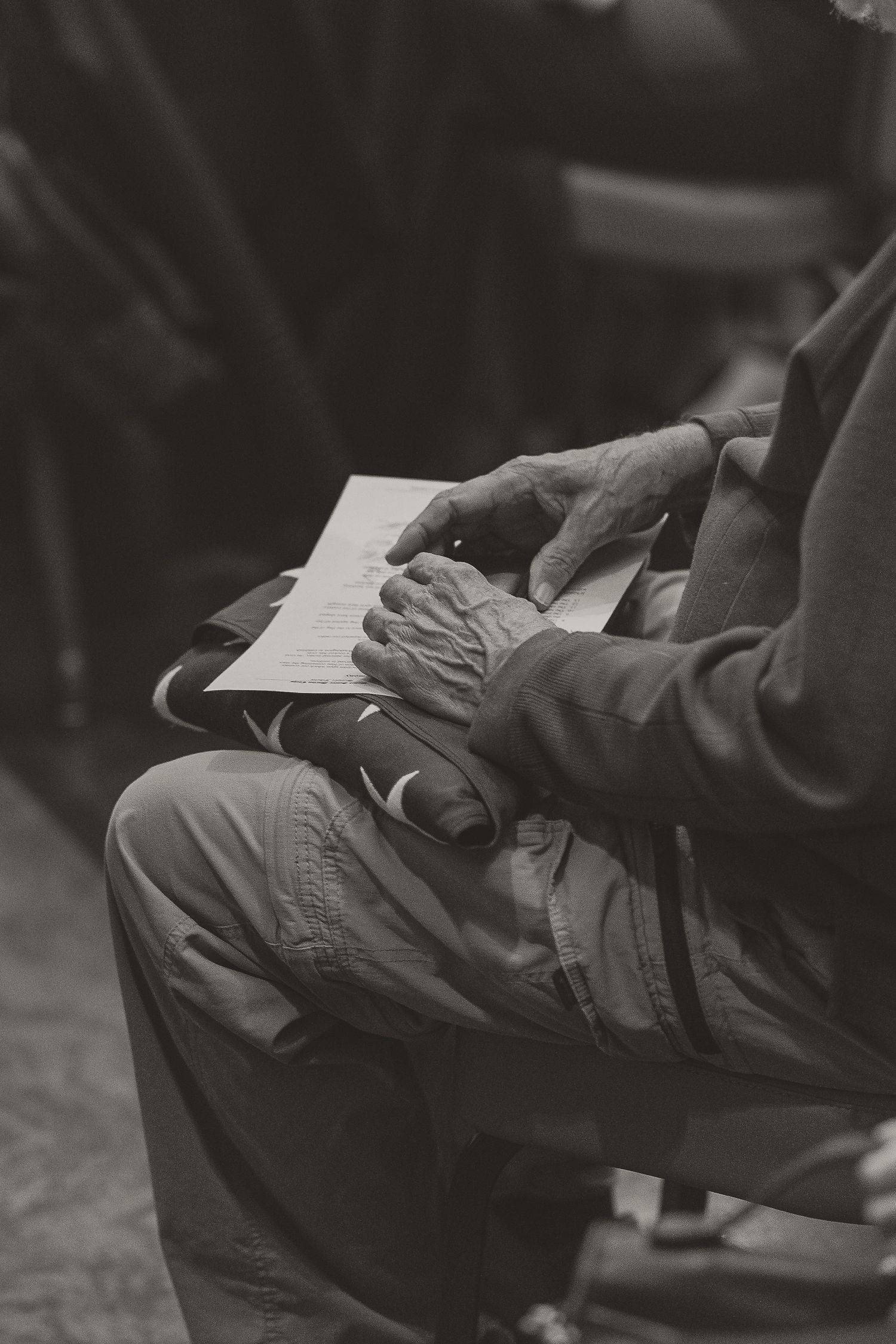 Elderly hands holding an open book in black and white photography.
