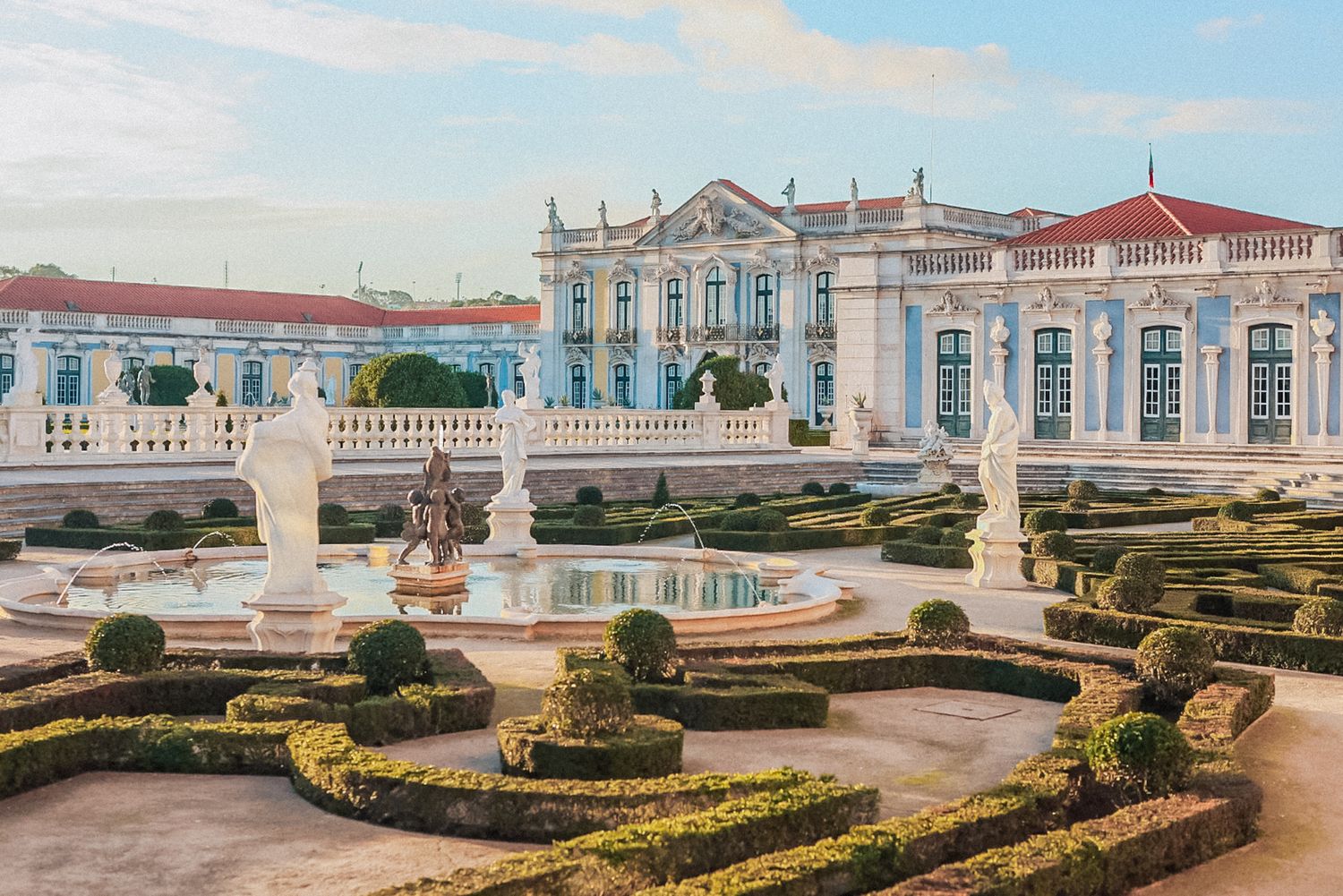 Elegant queluz palace in Portugal with ornate details against a light blue sky. captured by a Portugal destination wedding photographer
