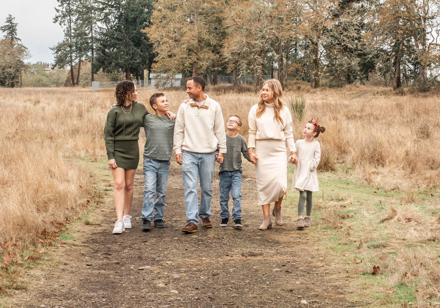 A group walks together along a rustic dirt path through golden grass and trees in autumn.