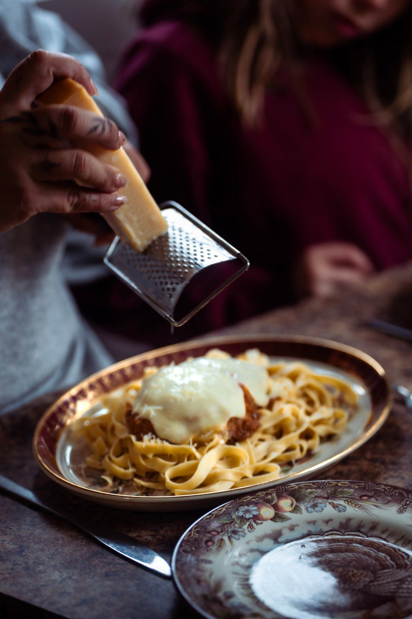 A person in a dark blue hoodie sits at a table with a large plate of poutine topped with gravy and cheese curds.