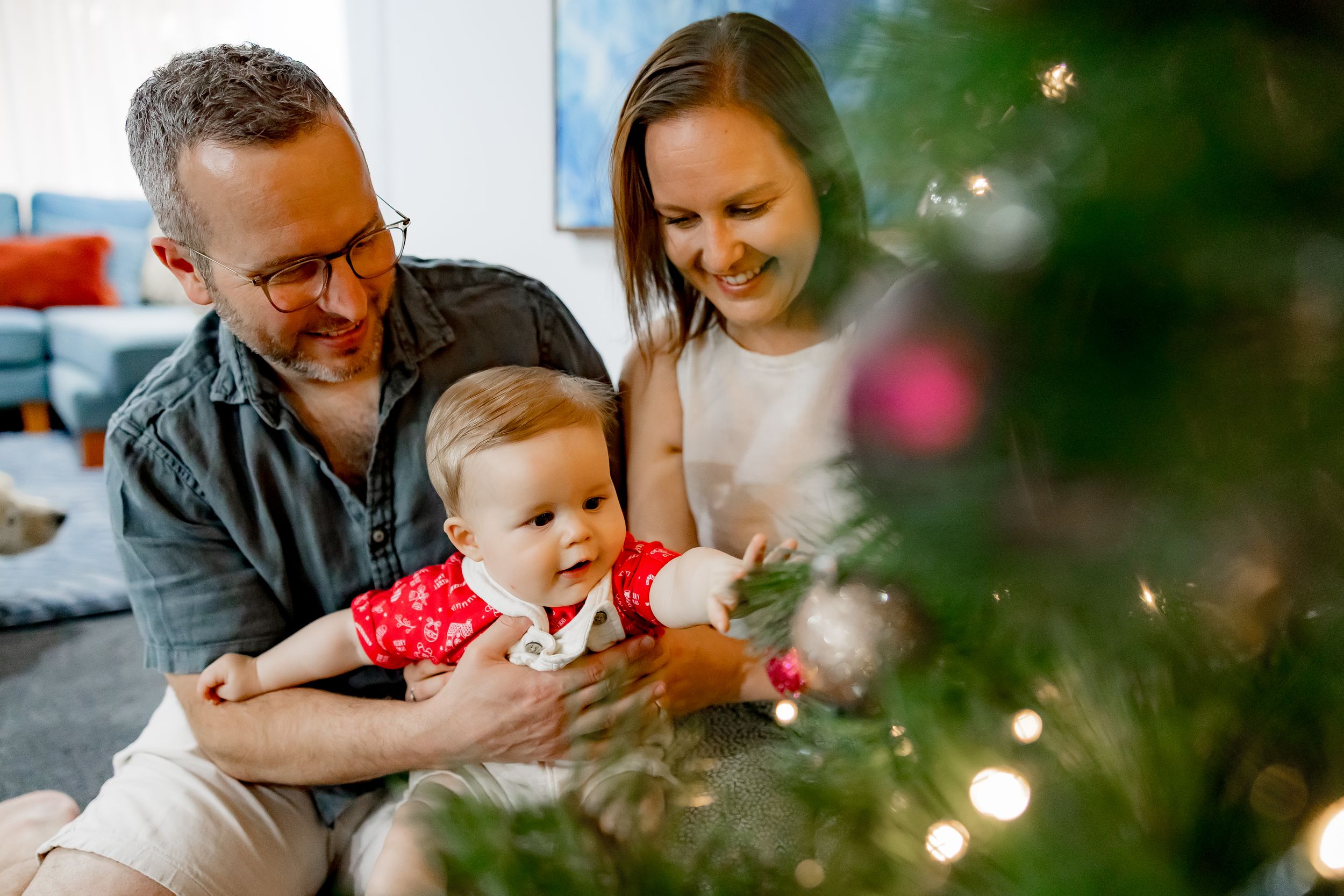 Family enjoying holiday moments together around a Christmas tree with twinkling lights and decorations.