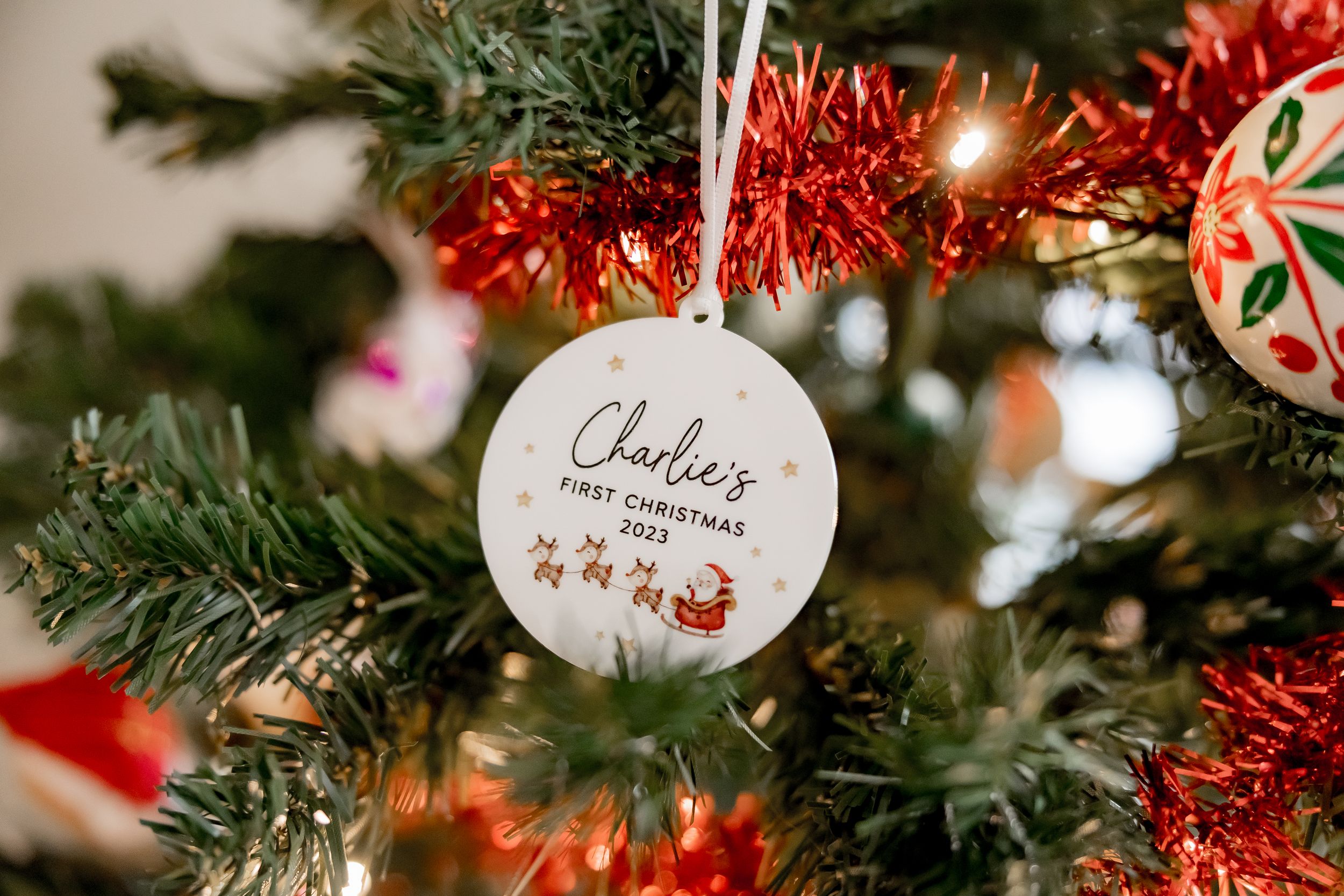 Christmas tree ornaments and decorations sparkle with red tinsel and white lights creating a festive holiday display.