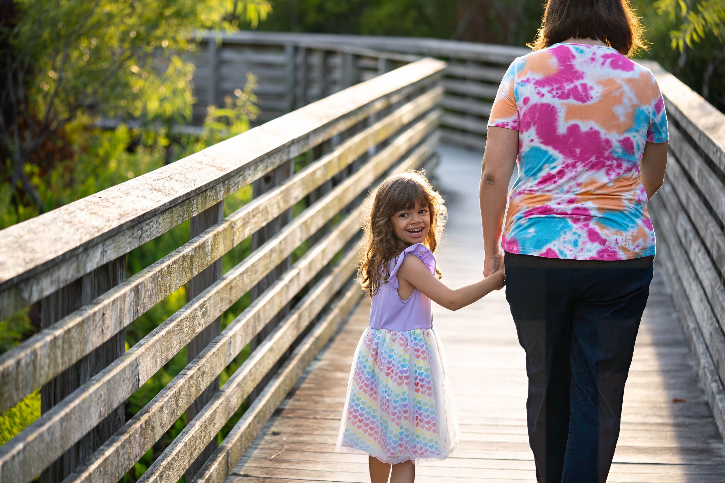 Toni and evelyn walking on the boardwalk of juno dunes natural area during a family session in juno beach florida