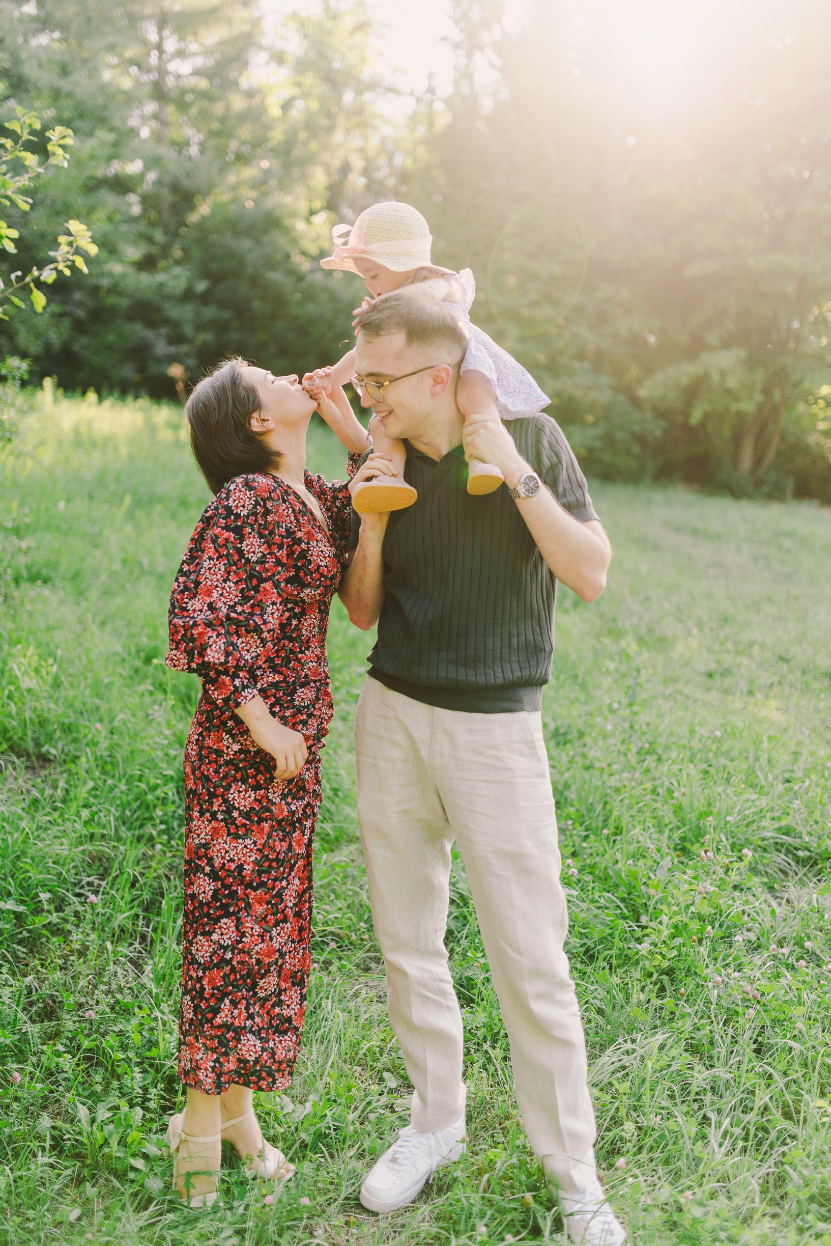 Family sharing joyful interactions in a sunlit meadow during golden hour.