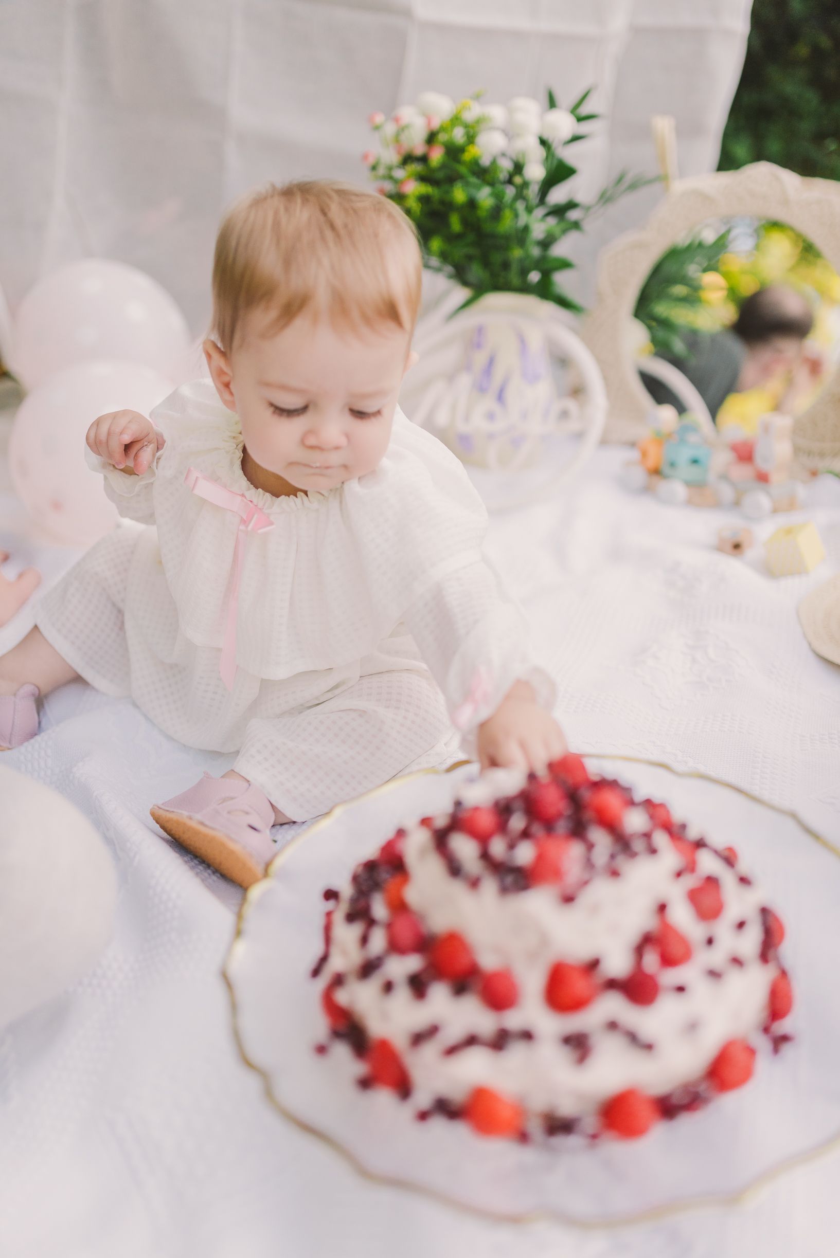 White cake decorated with fresh berries and cream on an elegant plate.