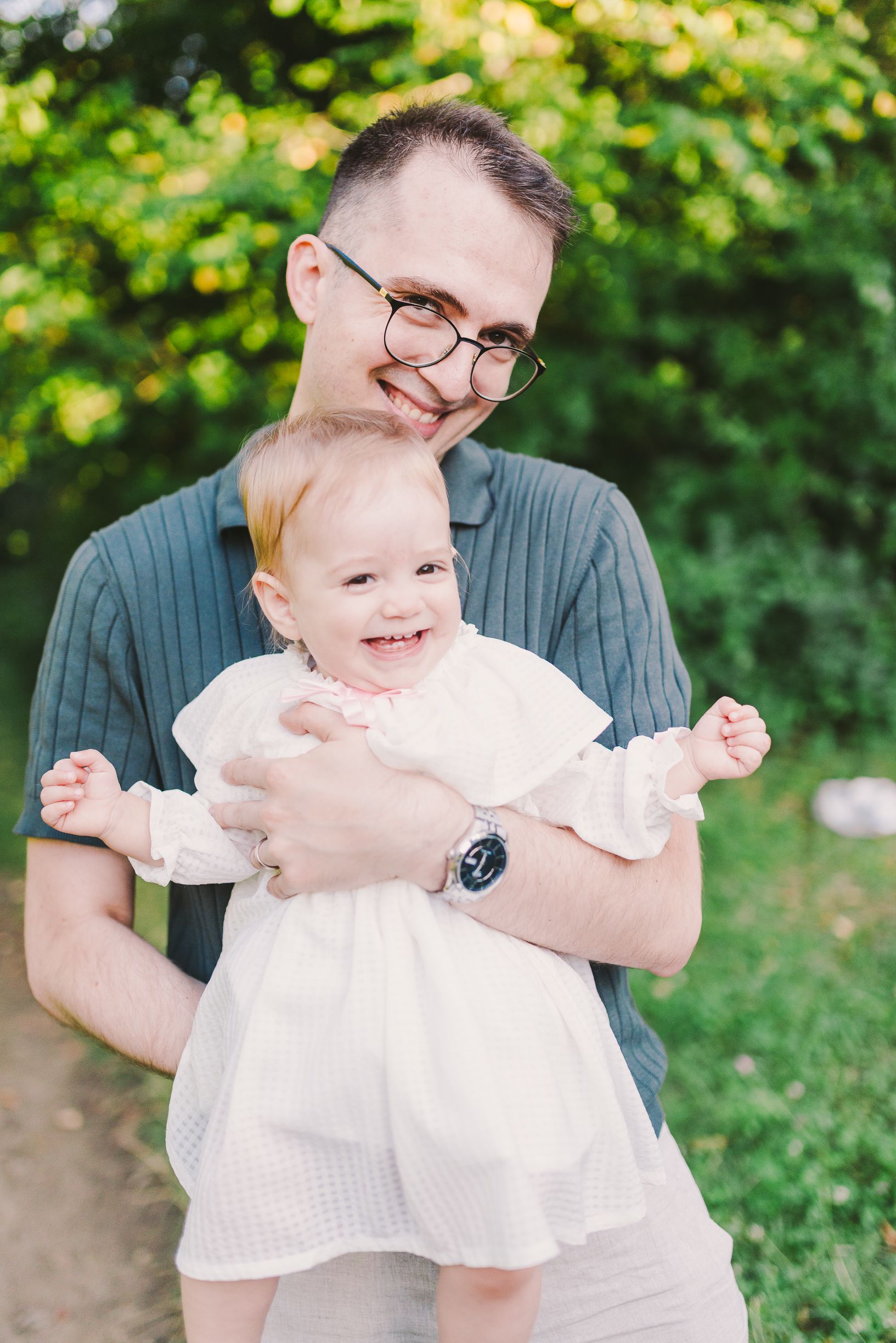 Candid outdoor family photoshoot in a green summer setting.