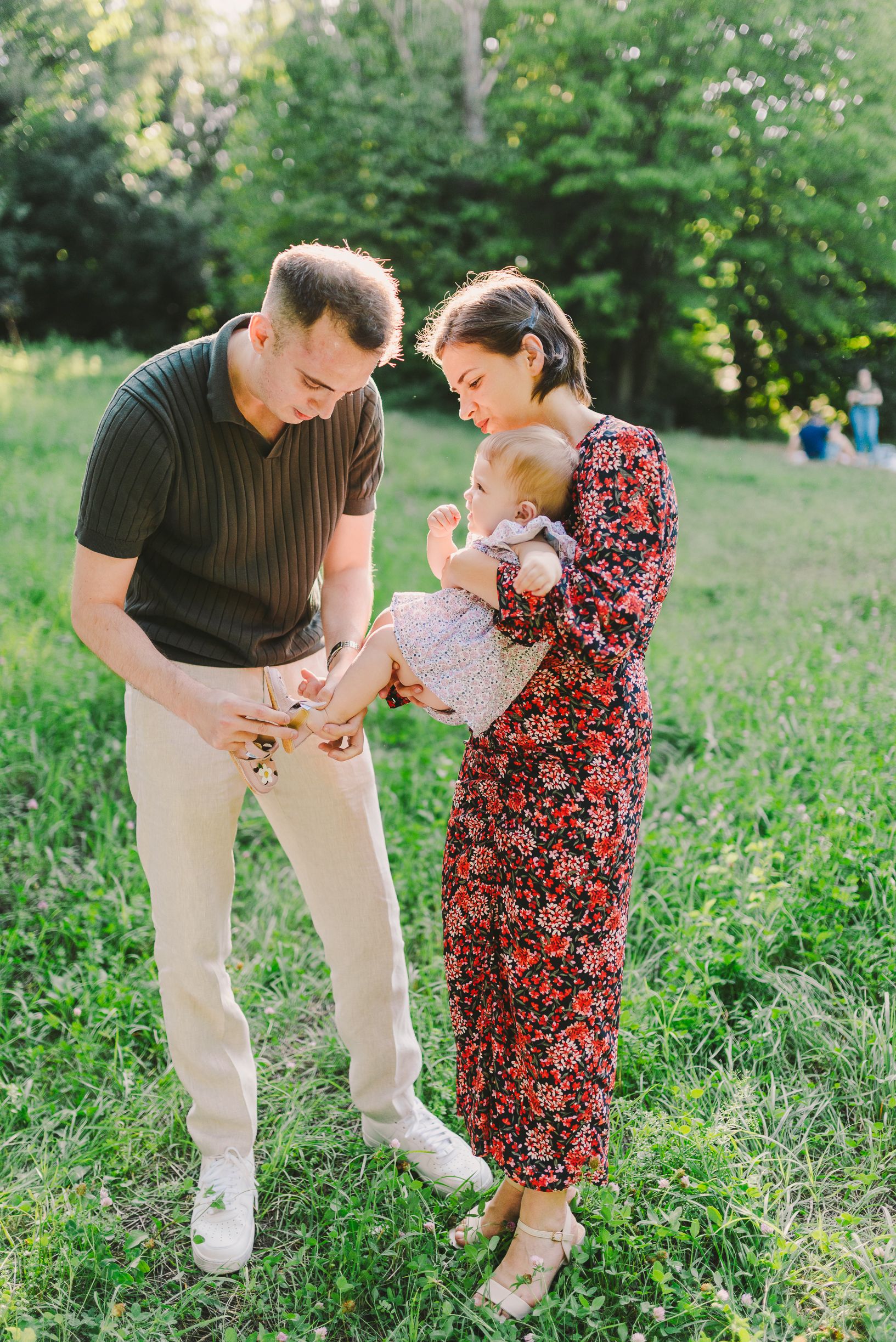 Family enjoying a playful moment together in a lush green park setting.