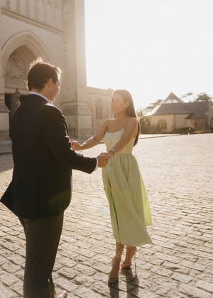 A couple dances together on cobblestone streets at sunset, creating a romantic silhouette against the warm light.