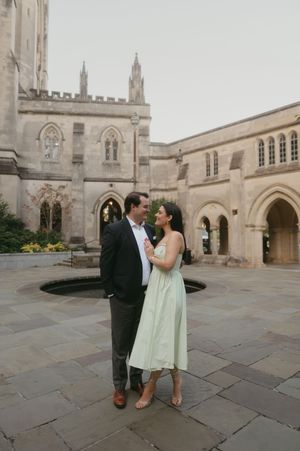 Elegant couple embracing in a stone courtyard of a historic cathedral with arched architecture.